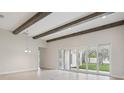 Bright living room has beamed ceiling, tiled floors, view of back yard and modern chandelier at 4535 Foley Grove Dr, Valrico, FL 33596