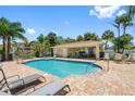 Community pool area featuring a covered seating area, brick patio, and lush landscaping at 5089 Royal Palms Way # 202, New Port Richey, FL 34652