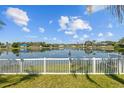 Picturesque backyard view of a serene lake behind a white picket fence at 5117 Spectacular Bid Dr, Wesley Chapel, FL 33544