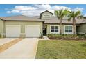 Lovely exterior featuring a two-car garage, well-maintained lawn and a tropical palm tree at 6850 Ripple Pond Loop, Zephyrhills, FL 33541