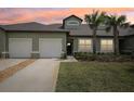Charming exterior showcasing a two-car garage, well-maintained lawn and a tropical palm tree at 6850 Ripple Pond Loop, Zephyrhills, FL 33541