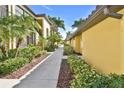 Exterior walkway with lush tropical landscaping including palm trees and manicured shrubbery at 7305 River Hammock Dr # 204, Bradenton, FL 34212
