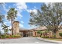 Beautifully landscaped exterior with tropical trees, colorful plants, and a charming entry tower at 8403 Grand Estuary Trl # 204, Bradenton, FL 34212