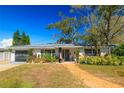 Inviting single-story home featuring an attached garage, brick walkway, lush plantings, and a welcoming entrance at 1131 60Th Ave S, St Petersburg, FL 33705