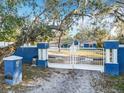 Private property with blue fence, white gate and columns, lush landscaping, and spacious driveway at 11335 Mcmullen Loop, Riverview, FL 33569