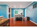 Living room featuring wood floors, a dining table, teal walls, and an open layout to the kitchen and florida room at 11970 80Th Ave, Seminole, FL 33772