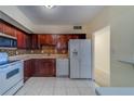 This well-lit kitchen features wood cabinets, stone countertops, and white appliances at 30 Turner St # 203, Clearwater, FL 33756