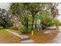 Corner lot featuring a white house with chain link fence, mature trees and yellow fire hydrant on a street corner at 3425 E Powhatan Ave, Tampa, FL 33610