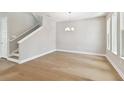 Open living room featuring hardwood floors, a modern chandelier, bright windows, and a white staircase at 4017 W North B St, Tampa, FL 33607