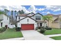 Charming two-story home with well-manicured lawn, beautiful landscaping and a red two car garage door at 4136 Shrewbury Pl, Land O Lakes, FL 34638