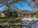 Charming single-story home featuring a three-car garage, lush landscaping, and a welcoming entrance at 6107 Ibispark Dr, Lithia, FL 33547