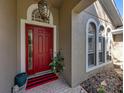 Inviting front entrance featuring a vibrant red door, decorative lighting, and elegant architectural details at 6107 Ibispark Dr, Lithia, FL 33547