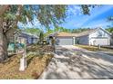 Lovely home with a well-manicured lawn, mature trees, and a long driveway leading to an attached two-car garage at 7459 Oxford Garden Cir, Apollo Beach, FL 33572