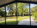 View from a screened porch to a grassy back yard with a concrete pad and mature trees beyond at 9377 Preston Rd, Brooksville, FL 34601