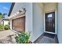 A front entry door and a garage with a brick driveway and a decorative pergola above the doors at 16868 Scuba Crest St, Wimauma, FL 33598