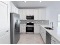 Modern kitchen featuring stainless steel appliances, white cabinets and a tile backsplash at 22442 Peachland Blvd, Port Charlotte, FL 33954