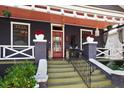 Close-up view of the front porch featuring a decorative railing, potted plants, and a bright red door at 1207 E Columbus Dr, Tampa, FL 33605