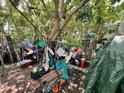 Backyard is filled with disorganized items and debris under a canopy of trees, showing neglect and overgrowth at 12588 128Th Ave, Largo, FL 33774