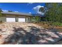 Charming home featuring a well-manicured front yard and a brick driveway leading to a two-car garage on a sunny day at 2215 River Ridge Dr, Sarasota, FL 34239