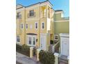 Attractive yellow two-story townhome showcasing a black wrought-iron balcony and manicured greenery at 2307 Victoria Gardens Ln, Tampa, FL 33609