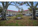 Apartment building exterior with a large lawn, trees, and parking at 2430 Florentine Way # 44, Clearwater, FL 33763