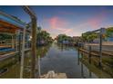 View from the dock showing a boat lift, canal, and waterfront neighborhood with beautiful sunrise at 4911 W Melrose S Ave, Tampa, FL 33629