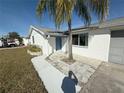 Charming single-story home with a well-manicured lawn, palm tree, and a blue front door at 6241 Seabreeze Dr, Port Richey, FL 34668