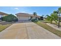 View of the home's wide driveway leading to an attached garage, surrounded by well-maintained landscaping at 701 Baltusrol Way, Sun City Center, FL 33573