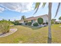 A well-kept lawn surrounds this charming house that has nicely trimmed bushes and Florida palm trees at 701 Baltusrol Way, Sun City Center, FL 33573