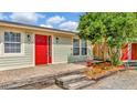 Charming single-story home with light siding, red door, manicured landscape, and inviting entryway at 7421 Andre Dr, Zephyrhills, FL 33541