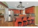 A modern kitchen with a stainless steel refrigerator, complementary red cabinets, and a breakfast bar with seating for entertaining at 7421 Andre Dr, Zephyrhills, FL 33541