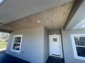 Inviting front porch with wood ceiling details, featuring a glass front door and stylish exterior lighting at 8204 Chimney Rock Dr, Webster, FL 33597