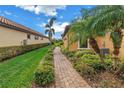 Beautiful landscaping with a brick path to the front, the grass is nicely trimmed, and a palm tree at 10446 Highland Park Pl, Palmetto, FL 34221