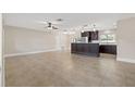 Spacious living room with tile flooring and ceiling fan, open to kitchen island with bar seating and pendant lighting at 1180 Eden Isle Ne Blvd, St Petersburg, FL 33704