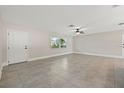 Bright, open living room with neutral walls, tile floor and ceiling fan, door to outside, and large window at 1180 Eden Isle Ne Blvd, St Petersburg, FL 33704