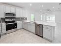 Modern kitchen with stainless steel appliances, white cabinetry, gray backsplash and a spacious quartz countertop at 134 Jade St, Rotonda West, FL 33947
