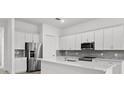 Modern kitchen with stainless steel appliances, white cabinets, and a center island with a quartz countertop at 17069 Moonflower Dr, Venice, FL 34293