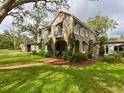 Charming two-story home with classic Spanish tile roof, black awnings, and professionally landscaped yard at 215 Willowick Ave, Temple Terrace, FL 33617