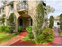 Inviting home exterior featuring a charming arched doorway, a small balcony, and vibrant, colorful landscaping at 215 Willowick Ave, Temple Terrace, FL 33617
