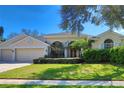 Attractive home with a two-car garage, lush green lawn, manicured bushes and a stone-accented facade at 4324 Auston Way, Palm Harbor, FL 34685