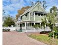 Charming two-story home with a wrap-around porch, mature landscaping, and a brick driveway at 6835 S Shamrock St, Tampa, FL 33616