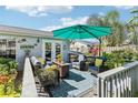 Enjoy outdoor living on the back deck with comfortable seating, shade umbrella, and lush tropical landscaping at 1015 Coldstream Ct, Tarpon Springs, FL 34689