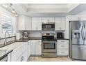 Modern kitchen features white cabinetry, stainless steel appliances, farmhouse sink, and attractive backsplash and countertops at 1015 Coldstream Ct, Tarpon Springs, FL 34689