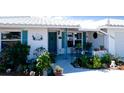 Charming home entrance featuring a lovely turquoise door, shuttered windows, and beautiful landscaping at 1320 Bottlebrush Dr, Bradenton, FL 34208