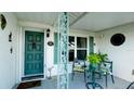 Inviting front porch with seating area, a glass-topped table, teal door, and decorative wrought iron accents at 1320 Bottlebrush Dr, Bradenton, FL 34208