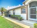 Side view of a home with a screened front door, lush landscaping, and neutral exterior paint at 13439 Norman Cir, Hudson, FL 34669