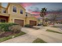 Townhome with two-car garage on a sunny day featuring a well-manicured lawn, an ample driveway, and mature palm trees at 2007 Hawks View Dr, Ruskin, FL 33570
