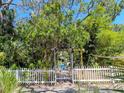 Welcoming white picket fence and arbor leading to a charming home with lush greenery at 5029 29Th S Ave, Gulfport, FL 33707