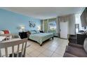 Bright bedroom features light blue walls, tile floor, queen bed, beach decor and a window overlooking a green field at 611 Destiny Dr # 304, Ruskin, FL 33570