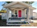 Inviting front porch with seating and vibrant pink door, offering a cozy curb appeal at 6907 N 12Th St, Tampa, FL 33604